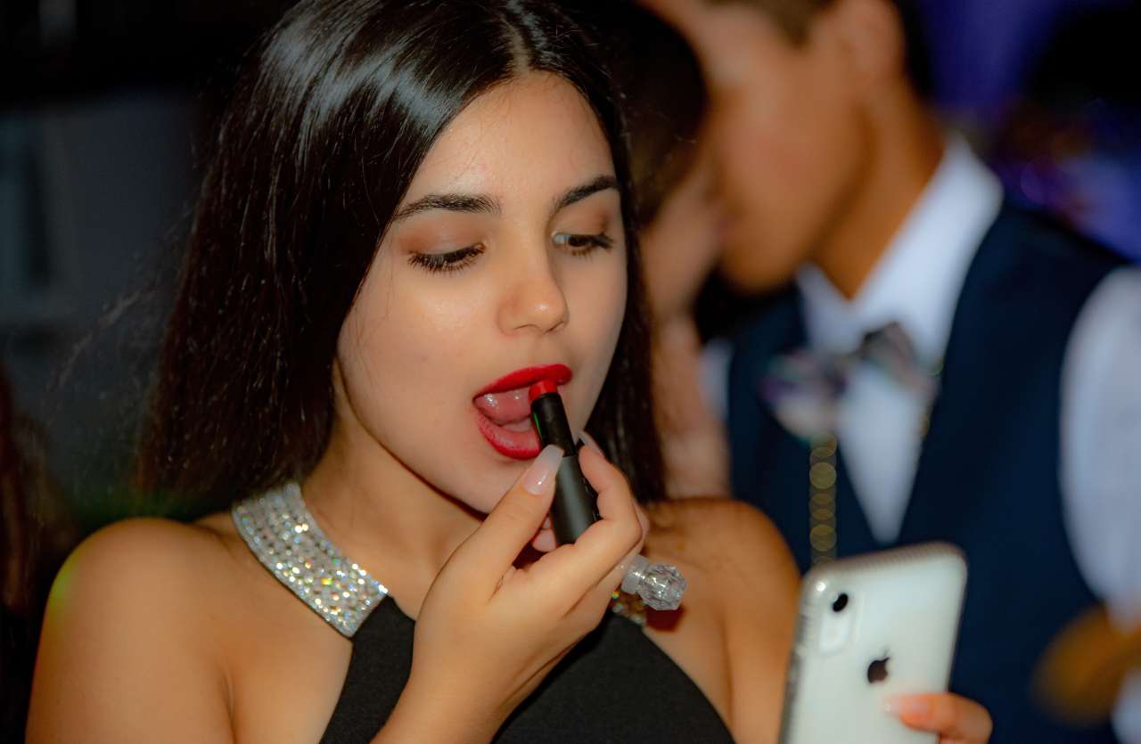 ragazza che mette rossetto specchiandosi nello smartphone