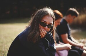 Ragazza con occhiali da sole isolata da amici sullo sfondo concetto amicizia tossica