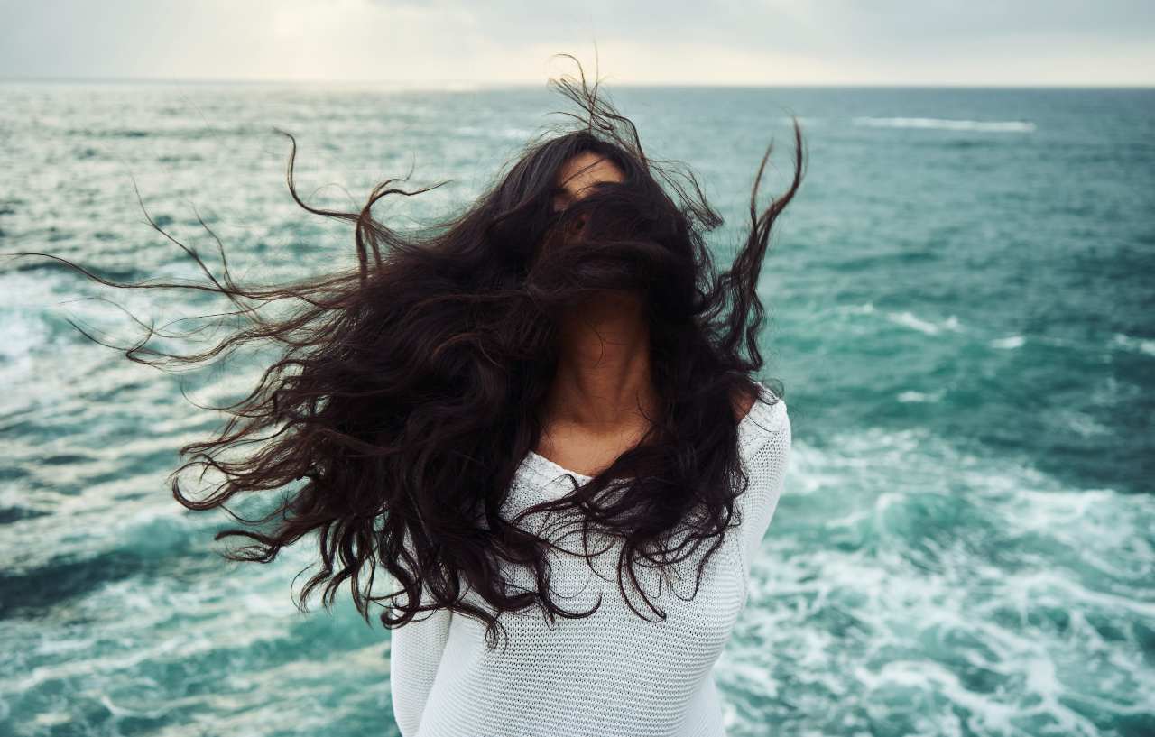 ragazza con capelli lunghi al vento in riva al mare