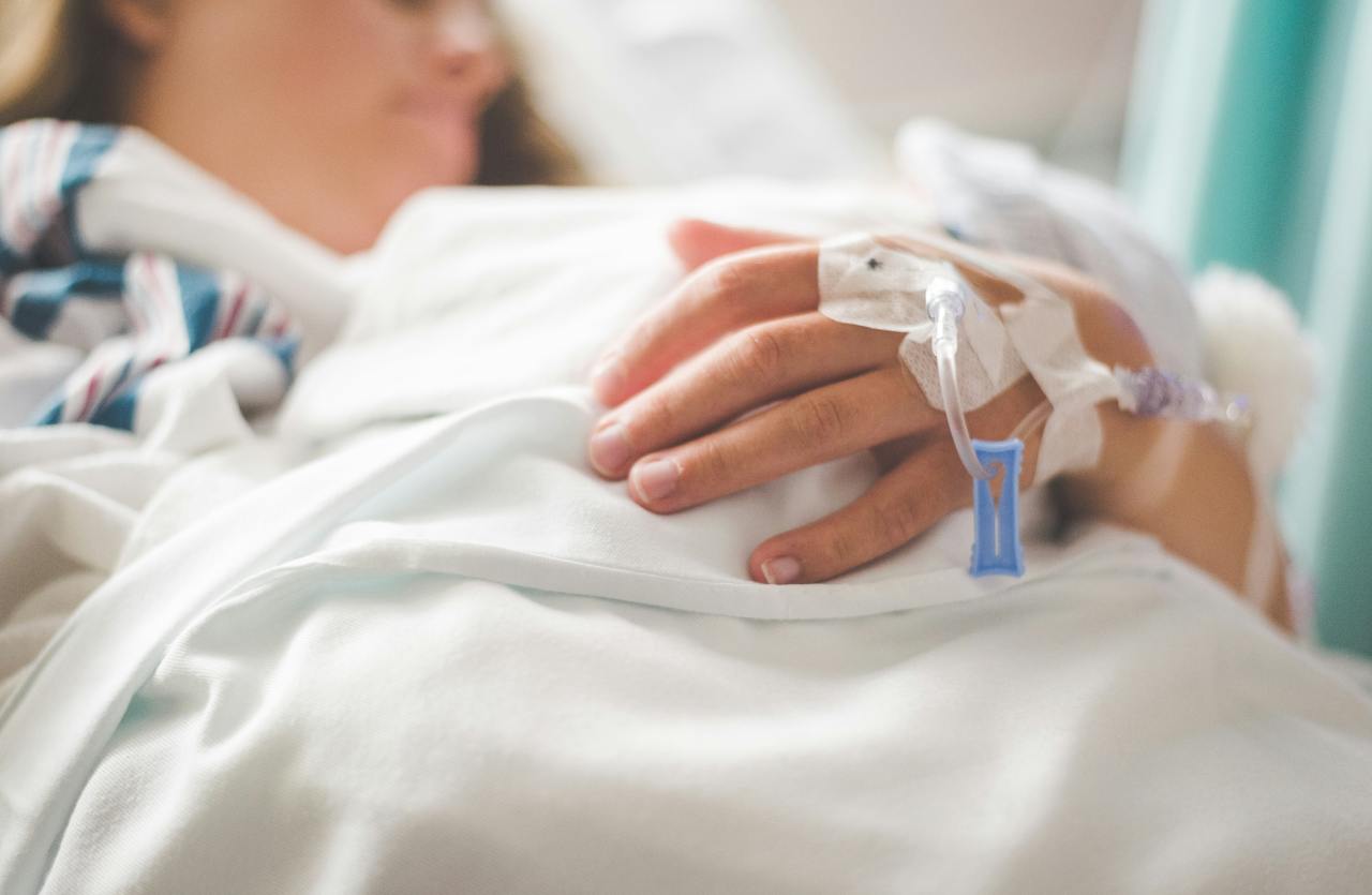 Primo piano di una mano con flebo a letto in ospedale per Sadfishing