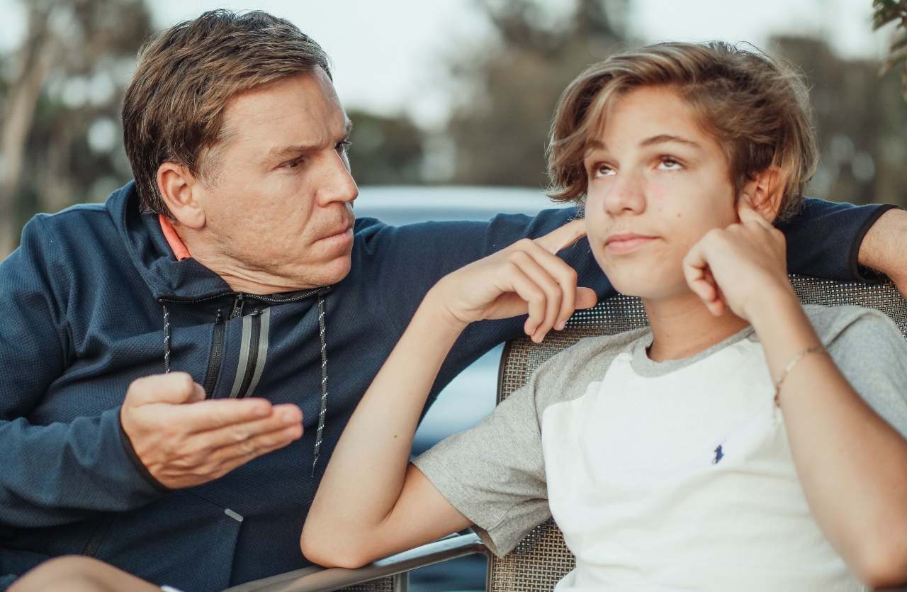 padre che parla al figlio che si copre le orecchie concetto cosa dicono i genitori