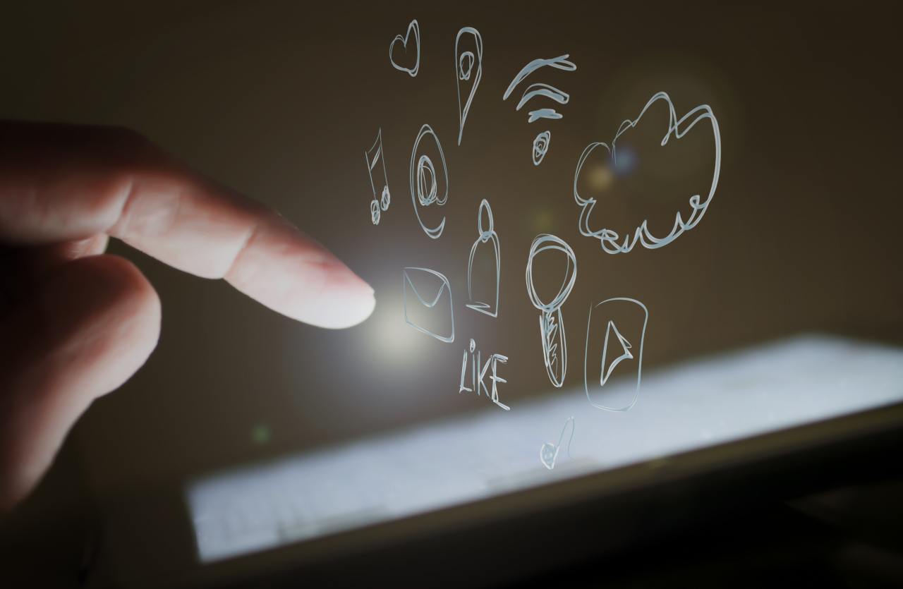 Dito che tocca lo schermo di uno smartphone al buio con icone social e la scritta "LIKE", concetto di tradimento su Instagram.