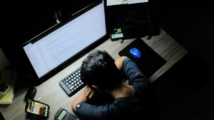 Inquadratura dall'alto di una persona esausta con la testa appoggiata sulla scrivania metafora per le truffe di phishing online