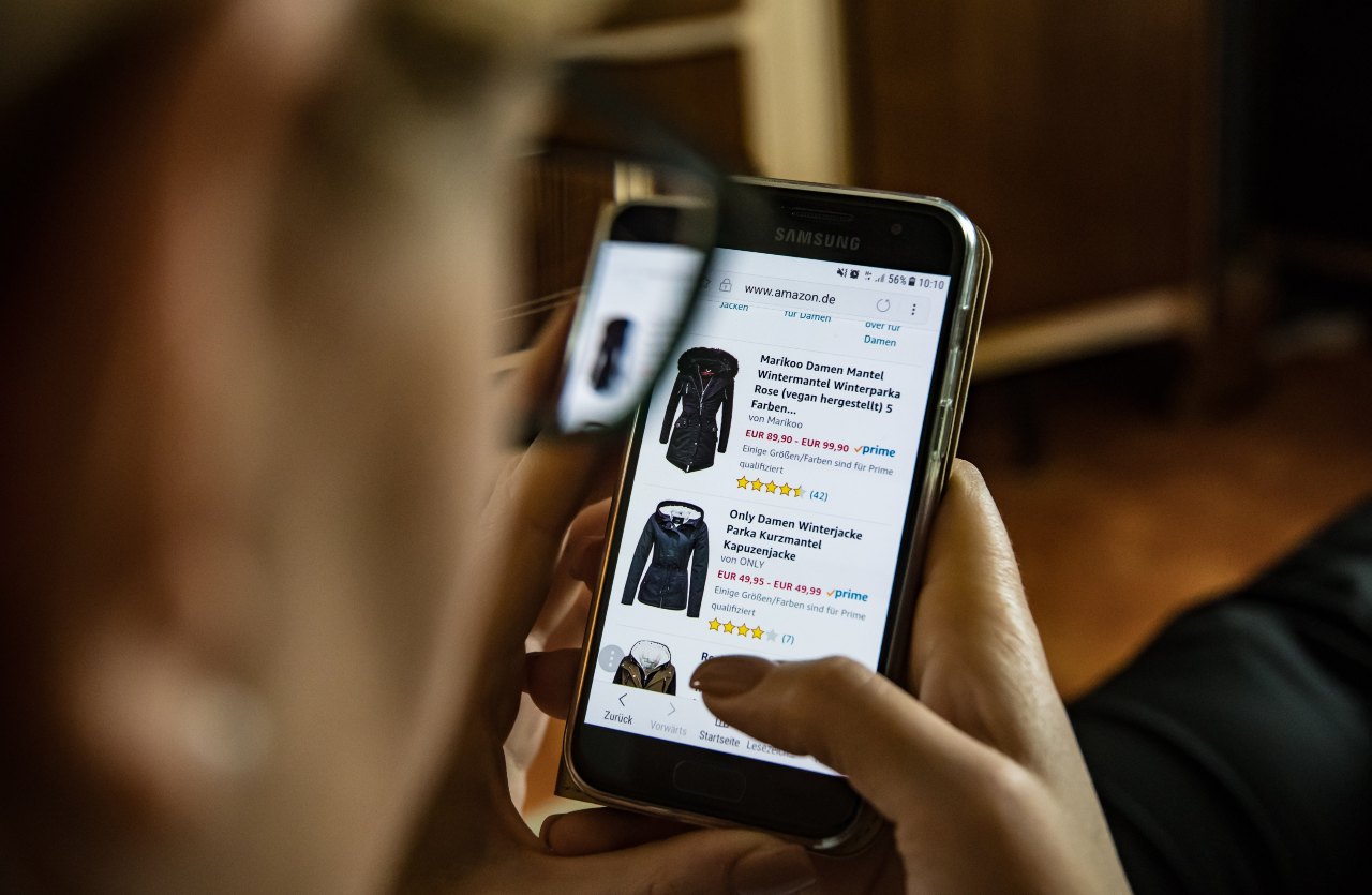 persona guarda giacche e vestiti a rate online su uno smartphone concetto compra ora paga dopo