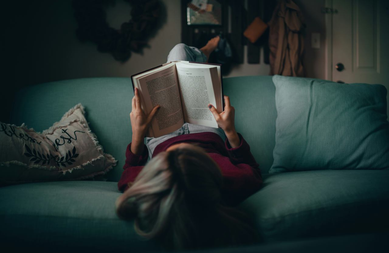 Ragazza sdraiata sul divano mentre legge un libro