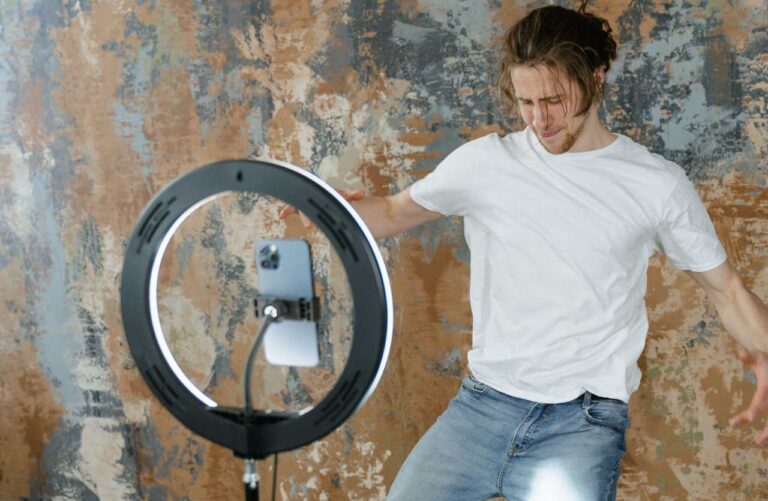 agazzo con maglietta bianca e jeans balla davanti a uno smartphone per il trend TikTok sul lavoro