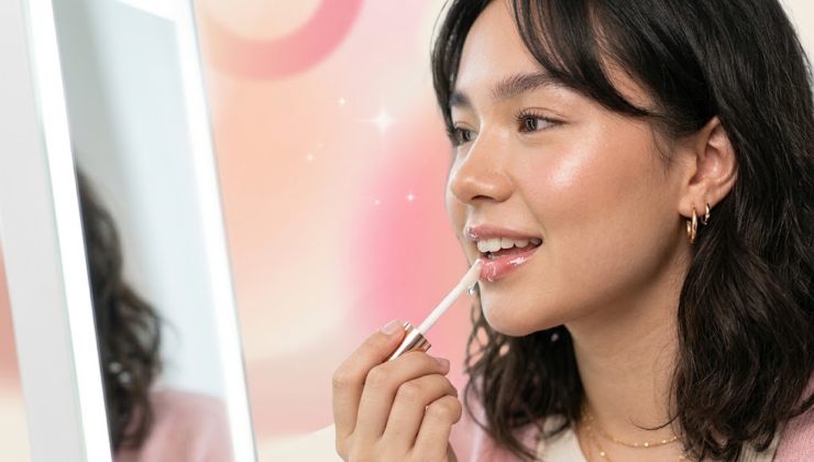ragazza che applica un gloss trasparente sulle labbra