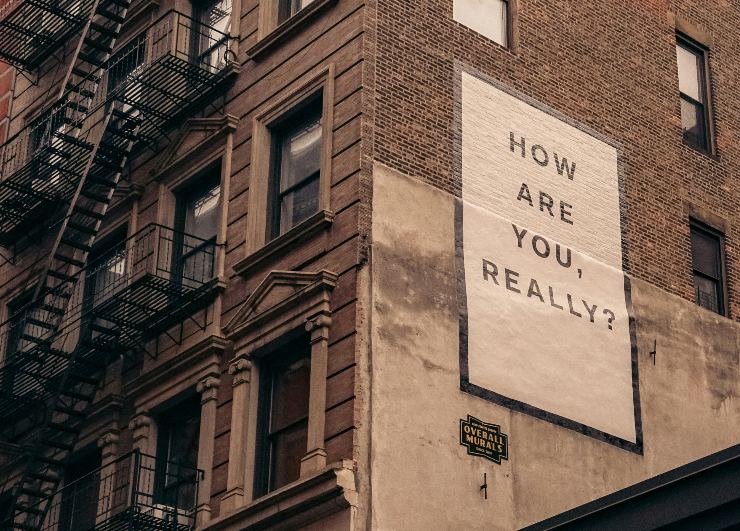 Murales su un palazzo di mattoni con la scritta "How are you, really?". Immagine concettuale sulla salute mentale